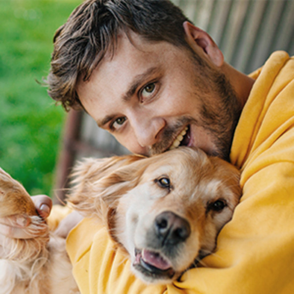 Image of a man and his dog playfully hugging.