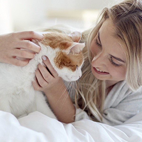 A happy young woman cuddles with her contented cat.