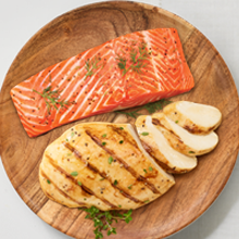 Salmon filet and sliced chicken breast on cutting board