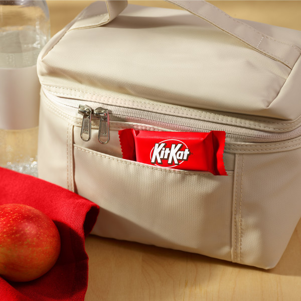 A snack size Kit Kat® candy bar poking out of a lunch box, alongside an apple and a water bottle
