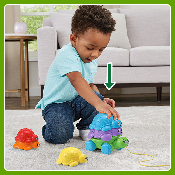 Kid stacks and nests toy turtles, creating a tower.