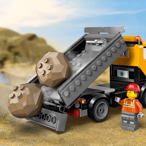 Dump truck has a tilting bed and 2 boulders secured with chains.
