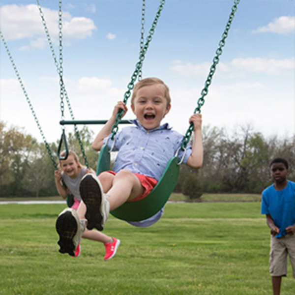 A child sitting on a swing kicking his feet to propel himself further