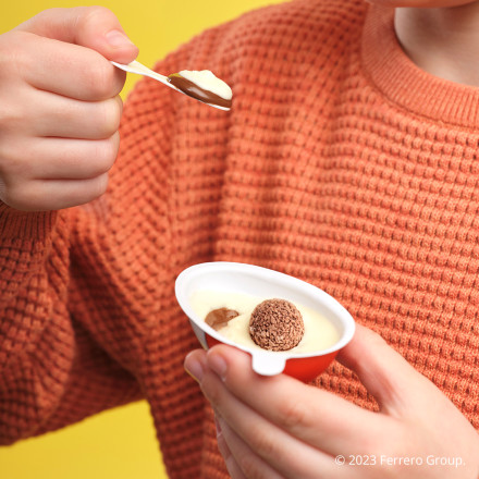 A kid eating a Kinder Joy egg. The treat—2 creamy layers, 2 chocolatey wafer bites filled with cream