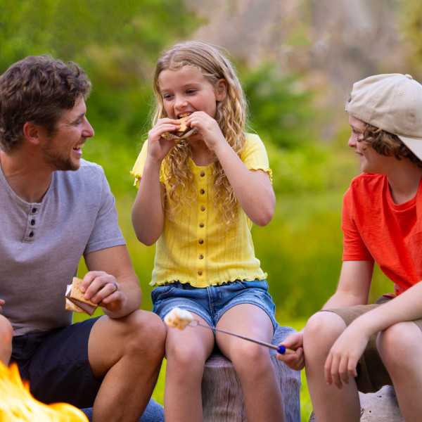 A family enjoying s'mores around a campfire as a tasty snack on a camping trip