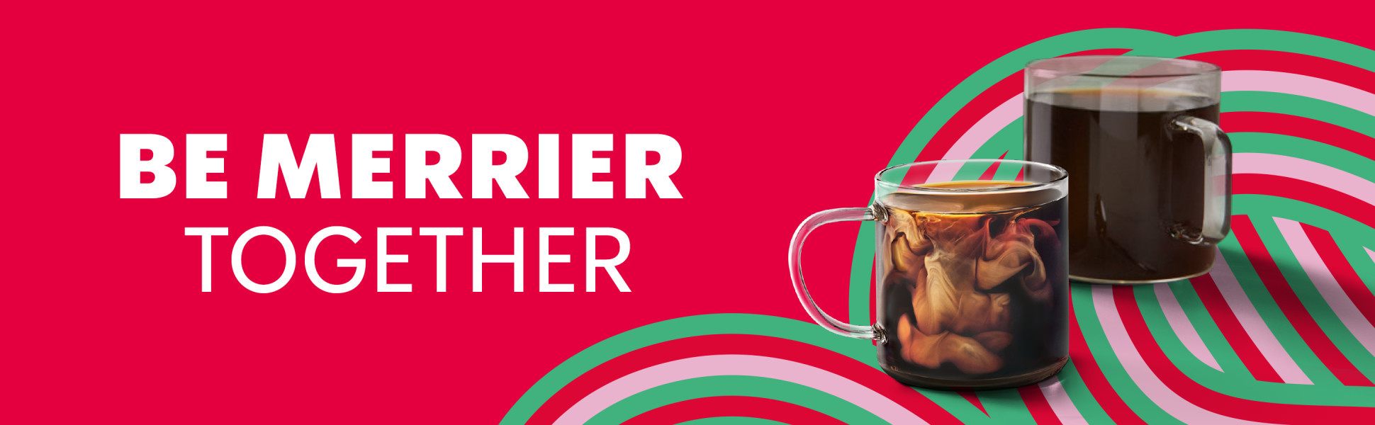2 clear glass mugs of coffee, 1 with cream swirling in it, in a festive setting. Be merrier together