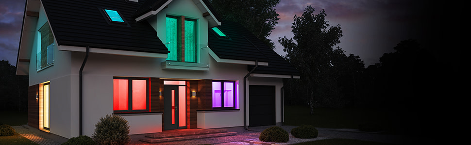 Exterior shot of a home with lights turned on in multiple colors showing 9w (60-Watt Replacement) RGBW Color Changing and Tunable White Medium Screw Base A21 Dimmable Alexa Google Smart Bulb.