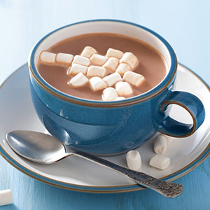 Hot chocolate on a plate with marshmallows in the cup. Spoon on the plate.