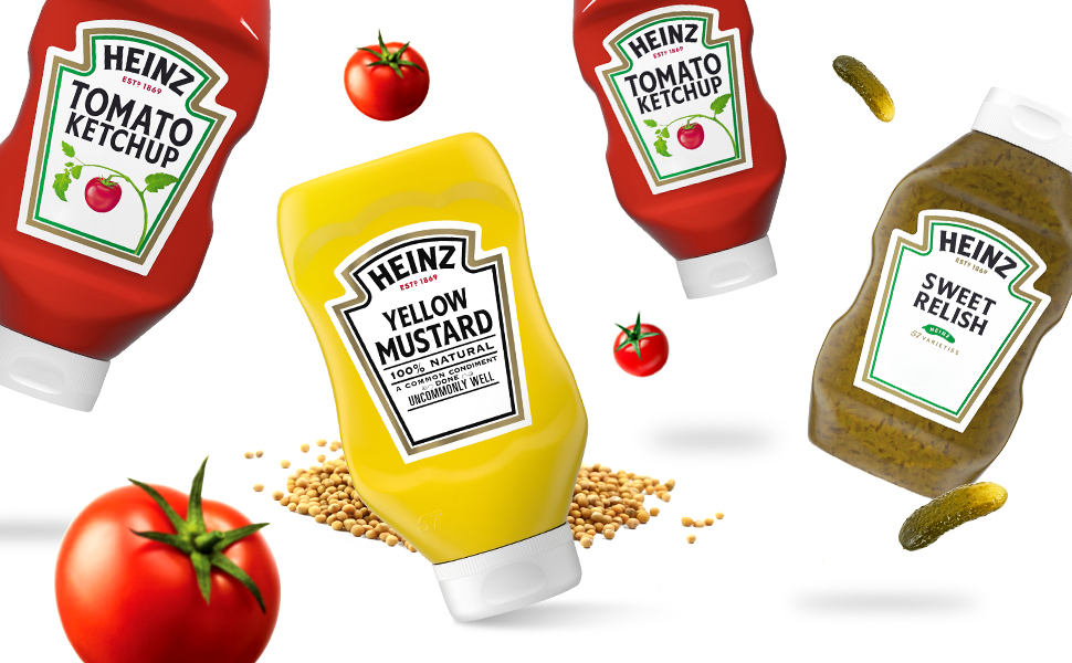 Photo of Heinz Tomato Ketchup bottles falling next to red ripe tomatoes with a white background.