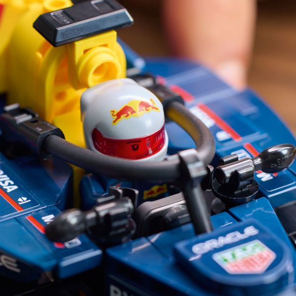 Driver wears a Red Bull outfit and a helmet with a wing.