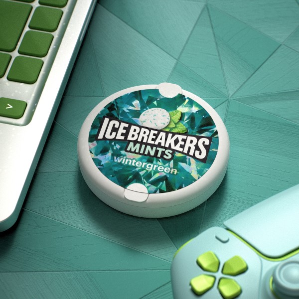 Ice Breakers wintergren flavored mints on a desk with a laptop and game controller
